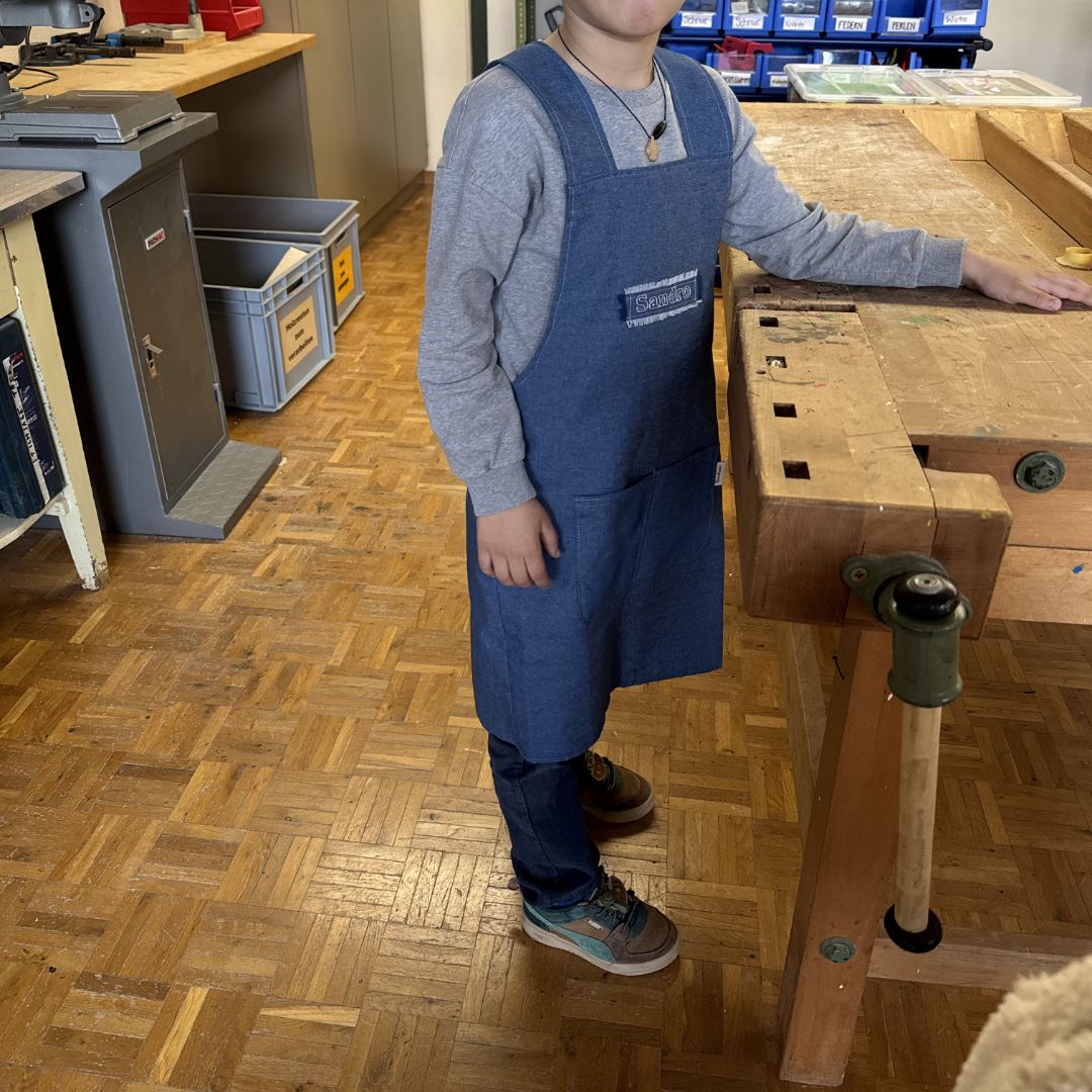 Kind trägt personalisierte Jeans-Kinderschürze beim Werkeln – robust & langlebig